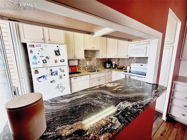 kitchen featuring white appliances, tasteful backsplash, dark stone countertops, dark wood-style flooring, and a sink