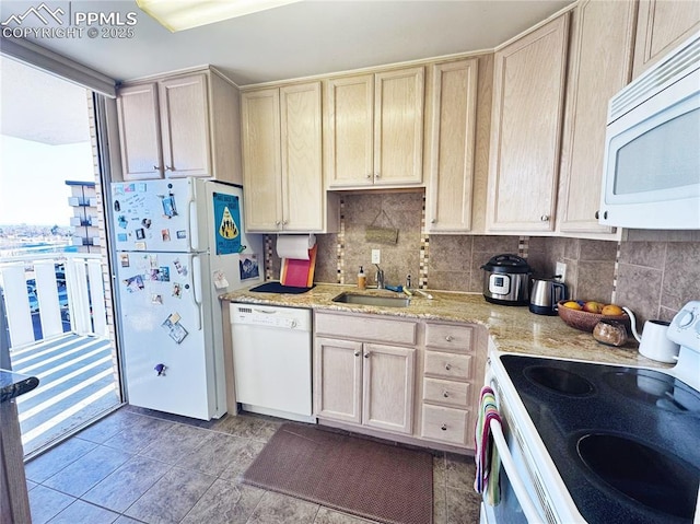 kitchen with light stone counters, white appliances, a sink, and decorative backsplash