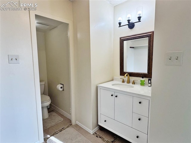 bathroom with toilet, tile patterned floors, baseboards, and vanity