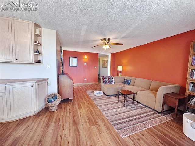 living area featuring ceiling fan, a textured ceiling, and wood finished floors