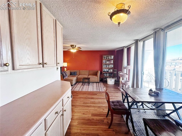 dining room with a ceiling fan, floor to ceiling windows, a textured ceiling, and wood finished floors