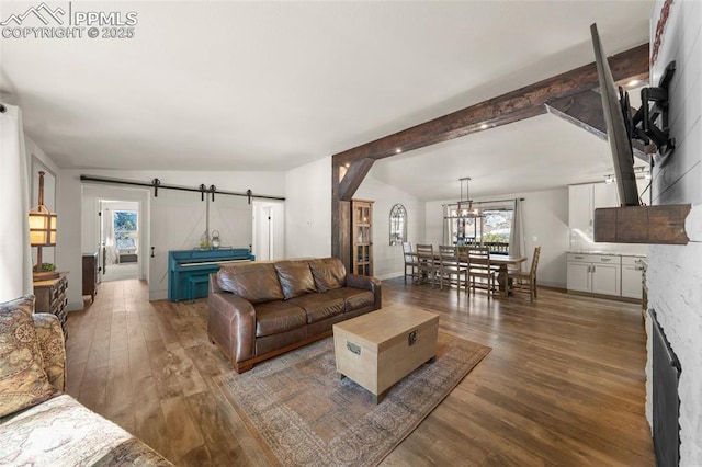 living area with a barn door, beam ceiling, a notable chandelier, and wood finished floors