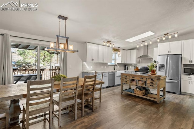 kitchen featuring decorative backsplash, dark wood-style floors, white cabinets, stainless steel appliances, and wall chimney exhaust hood