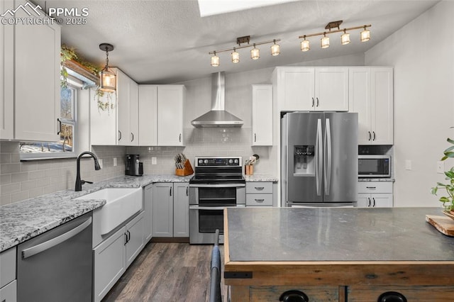 kitchen with decorative backsplash, dark wood-style floors, stainless steel appliances, wall chimney exhaust hood, and a sink