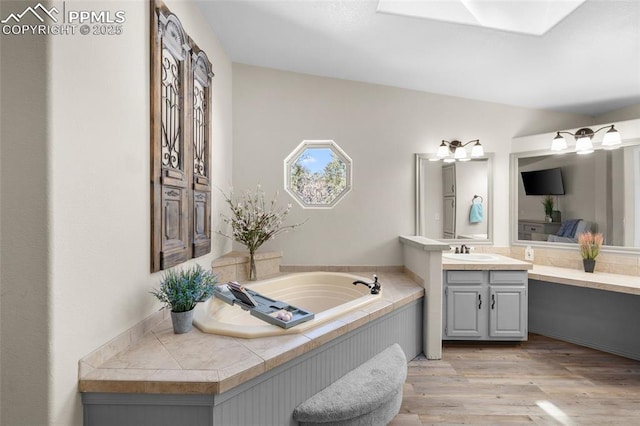 full bath featuring wood finished floors, vanity, and a bath