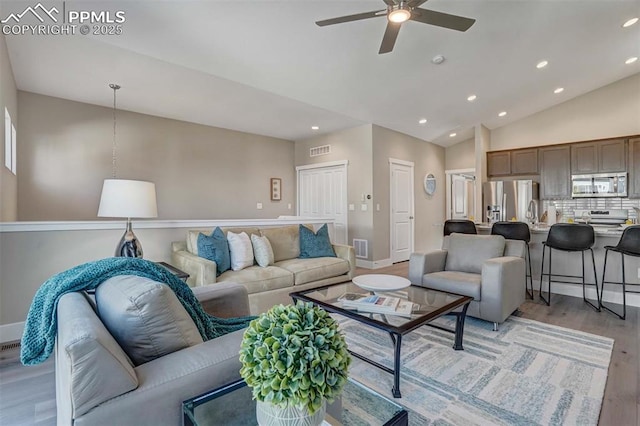 living area featuring recessed lighting, light wood-style floors, a ceiling fan, vaulted ceiling, and baseboards