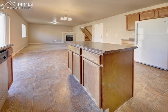 kitchen with dishwasher, a center island, freestanding refrigerator, an inviting chandelier, and a fireplace