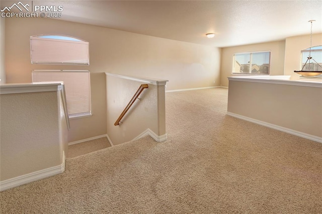 interior space featuring carpet, an upstairs landing, and baseboards