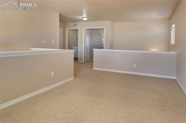 carpeted empty room featuring washer / dryer, visible vents, and baseboards