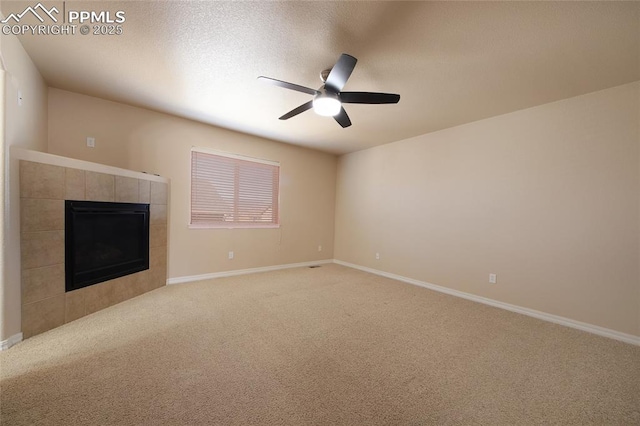 unfurnished living room featuring ceiling fan, a textured ceiling, a tile fireplace, light carpet, and baseboards