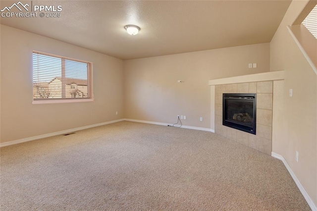 unfurnished living room featuring carpet floors, a tile fireplace, and baseboards