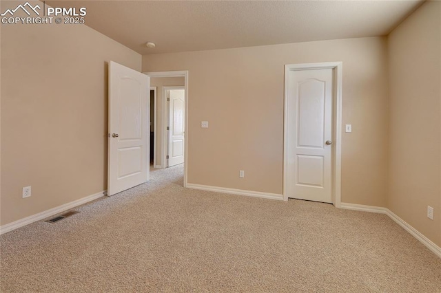 spare room featuring baseboards, visible vents, and light colored carpet