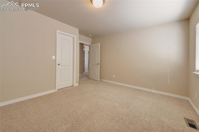 spare room featuring baseboards, visible vents, and light colored carpet