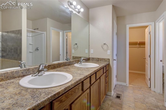 full bath with a sink, a shower stall, baseboards, and double vanity