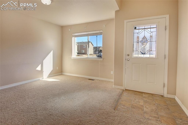 foyer with carpet flooring, visible vents, and baseboards