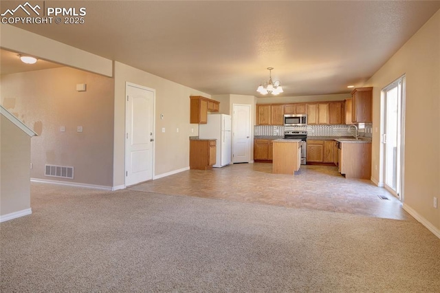 kitchen featuring a notable chandelier, light colored carpet, visible vents, open floor plan, and appliances with stainless steel finishes