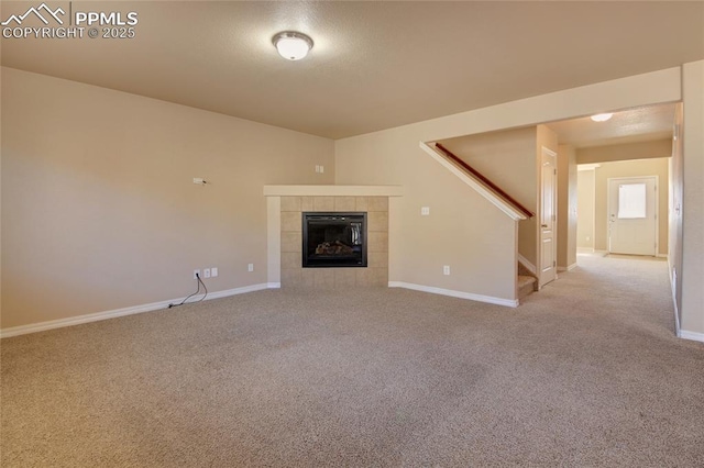 unfurnished living room featuring baseboards, stairway, carpet flooring, and a tile fireplace