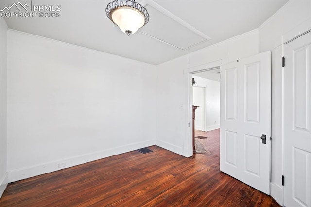 unfurnished bedroom featuring dark wood-style floors, visible vents, attic access, and baseboards