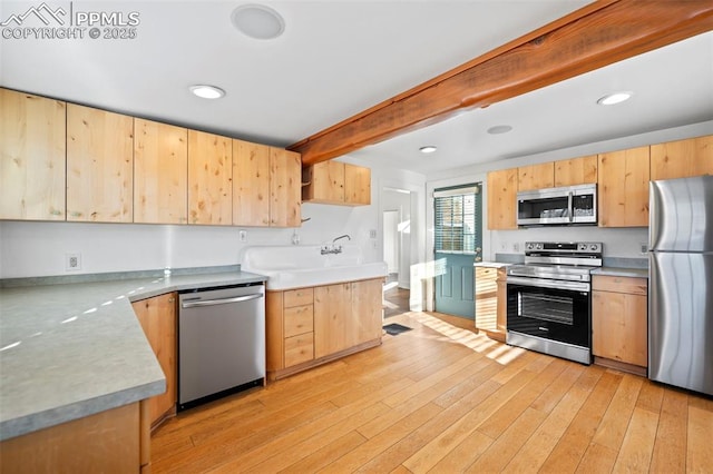 kitchen featuring light wood-style flooring, appliances with stainless steel finishes, beamed ceiling, light brown cabinets, and a sink