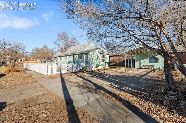 bungalow-style home featuring a fenced front yard, driveway, and a carport