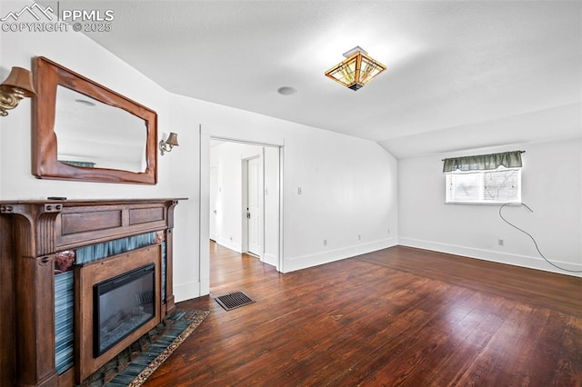 living room featuring lofted ceiling, wood-type flooring, baseboards, and a tiled fireplace