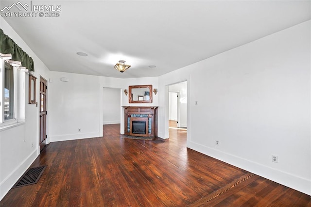 unfurnished living room featuring visible vents, a fireplace, baseboards, and wood finished floors