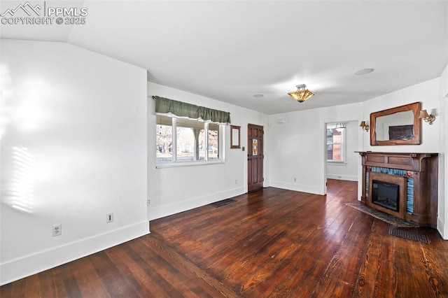 unfurnished living room with baseboards, hardwood / wood-style floors, a tile fireplace, and a healthy amount of sunlight