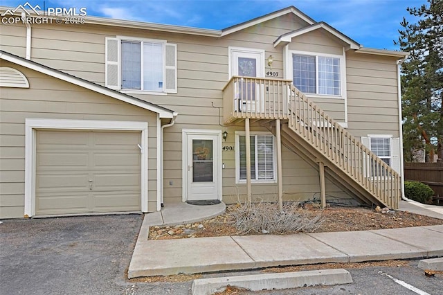 view of property featuring a garage, stairs, and aphalt driveway