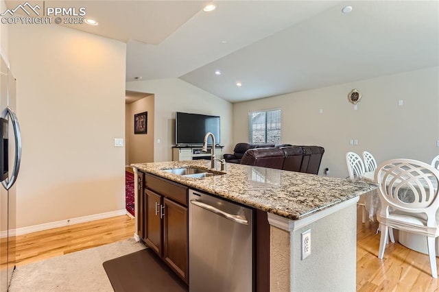 kitchen with lofted ceiling, a sink, stainless steel dishwasher, light stone countertops, and light wood finished floors