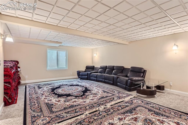 carpeted living area with a drop ceiling and baseboards