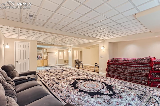 living area with a paneled ceiling and baseboards