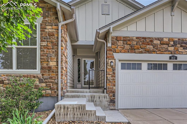 property entrance with a garage, stone siding, driveway, and board and batten siding