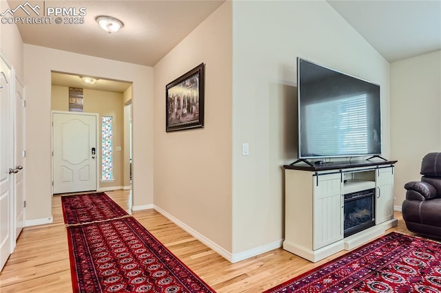 entryway featuring a glass covered fireplace, light wood-style flooring, and baseboards