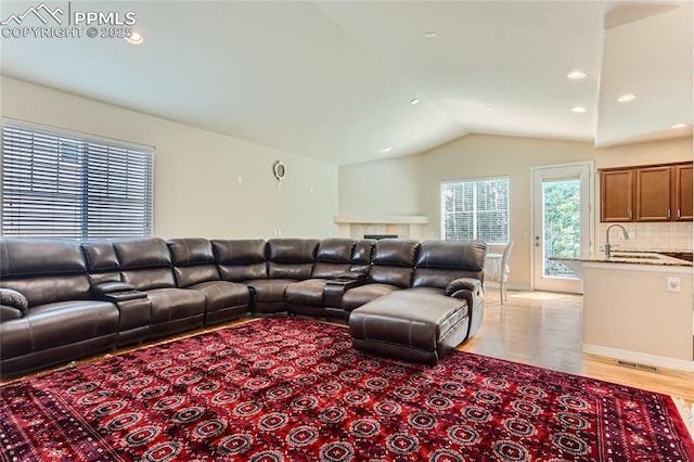 living room featuring light wood-style flooring, vaulted ceiling, and recessed lighting