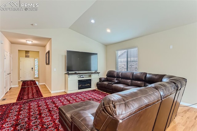 living room featuring recessed lighting, baseboards, vaulted ceiling, light wood-style floors, and a glass covered fireplace