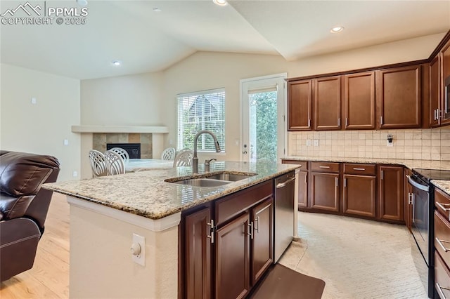 kitchen with light stone counters, range with electric stovetop, a sink, open floor plan, and dishwasher