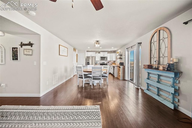 dining space featuring visible vents, dark wood-type flooring, a ceiling fan, and baseboards