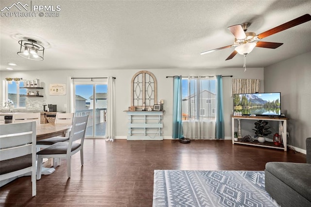 living room with a ceiling fan, a textured ceiling, baseboards, and wood finished floors