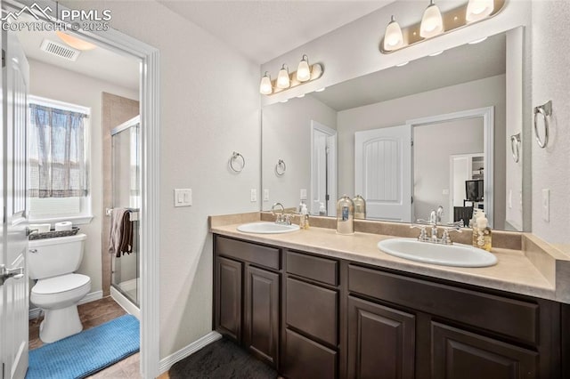 bathroom featuring double vanity, a stall shower, a sink, and toilet