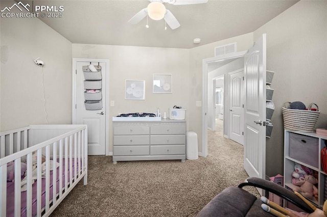 carpeted bedroom featuring a nursery area, visible vents, and ceiling fan