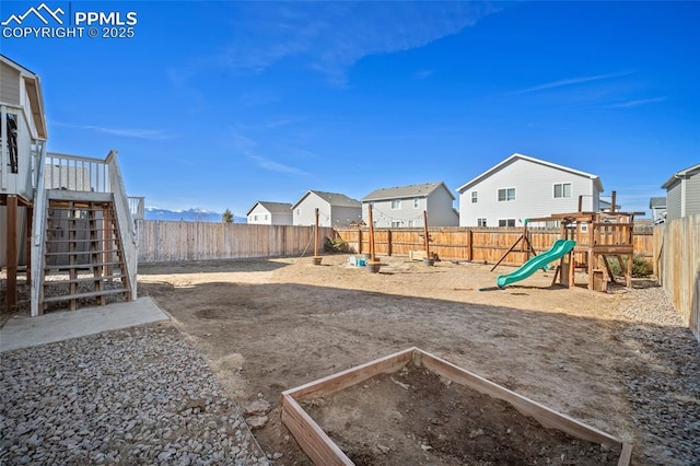 view of yard with stairway, a playground, a fenced backyard, and a vegetable garden