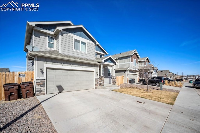 view of front of property featuring an attached garage, board and batten siding, fence, stone siding, and driveway