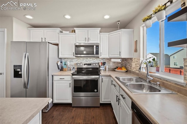 kitchen featuring stainless steel appliances, a sink, dark wood finished floors, and white cabinets