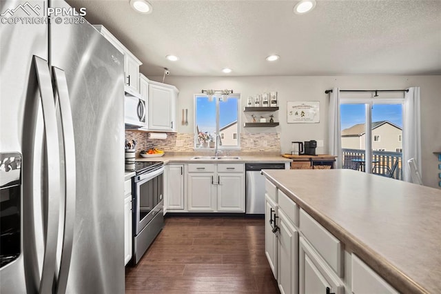 kitchen featuring appliances with stainless steel finishes, plenty of natural light, a sink, and dark wood finished floors