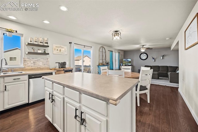 kitchen featuring dark wood-style floors, dishwasher, decorative backsplash, and a sink