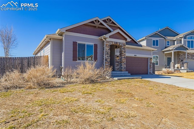 view of front of property with stone siding, fence, driveway, and an attached garage