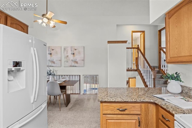 kitchen featuring white refrigerator with ice dispenser, light colored carpet, ceiling fan, and light stone countertops