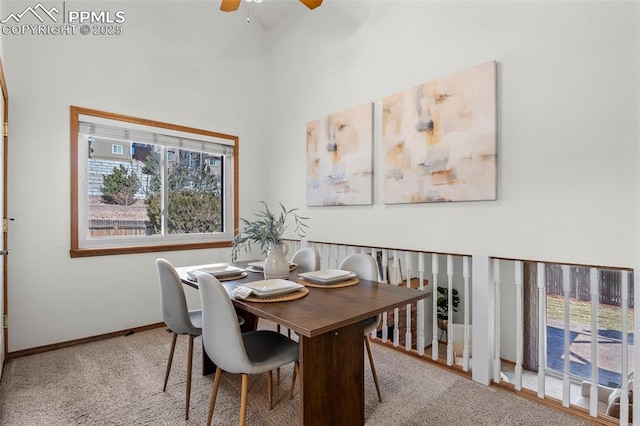 carpeted dining area with a high ceiling, a ceiling fan, and baseboards