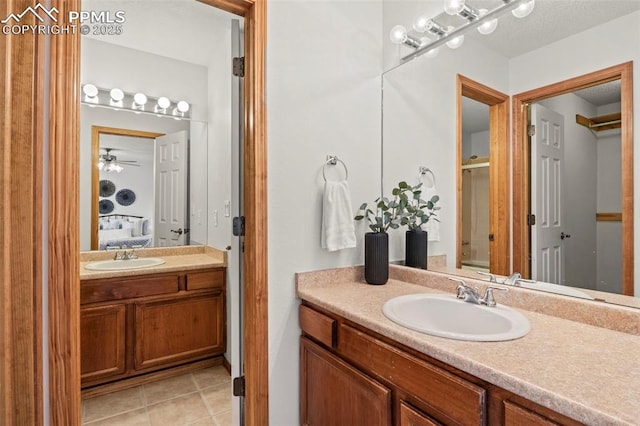 ensuite bathroom featuring a shower with shower door, connected bathroom, vanity, and tile patterned floors