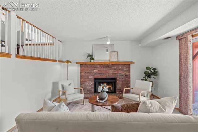 living room with a textured ceiling, a brick fireplace, visible vents, and baseboards